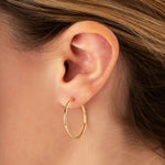 Close-up of an ear wearing a 25mm gold hoop earring 