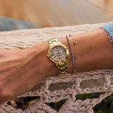 Gold watch on a wrist with a textured surface background