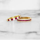 Two gold rings with ruby gemstones on a marble surface