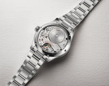 Silver watch with visible mechanical components on a light gray background
