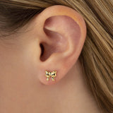 Gold bow-shaped earring worn on a person's ear